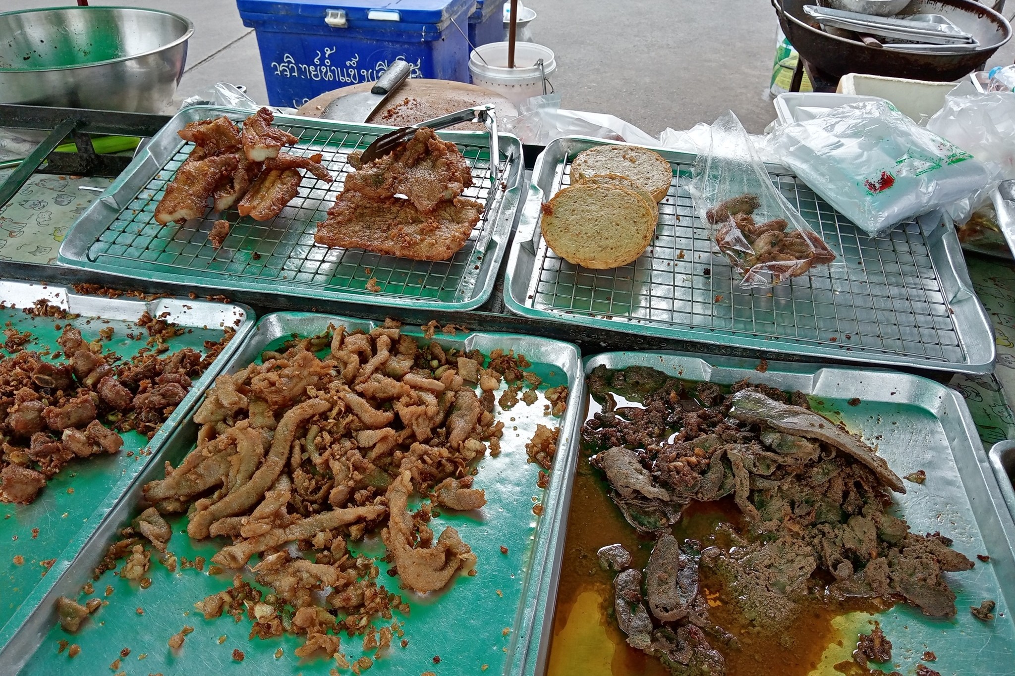 หมูทอดหลากแบบบนแผงตลาดพลู ธนบุรี ทอดจนกรอบทั้งชิ้นโดยไม่มีเปลือกแป้งหนา ญาติไทยที่ใกล้ทงคัตสึที่สุดในแนวคิด แต่ต่างกันที่เปลือก