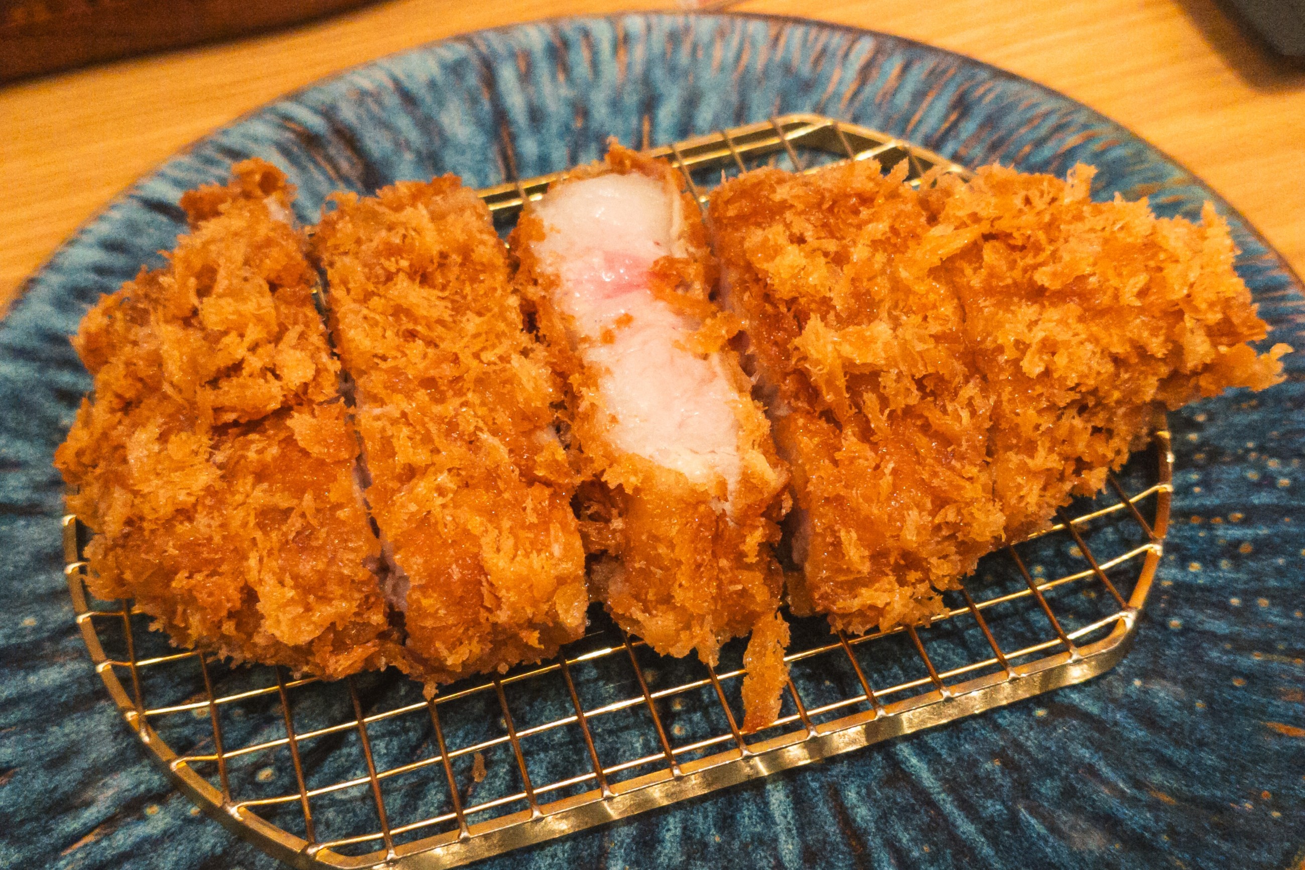 ทงคัตสึจากหมู Tokyo X หั่นแล้ววางบนตะแกรง เนื้อชมพูและไขมันแทรกที่เป็นเป้าหมายของโครงการผสมพันธุ์